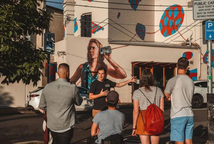 A group of people standing beside a building covered in art, listening to a tour guide. with Local Sauce Tours, Sydney, New South Wales © Local Sauce Tours