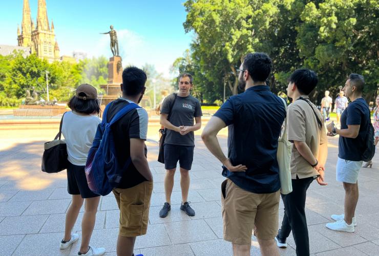 A group of people standing beside a fountain in a green park listening to a tour guide. with Local Sauce Tours, Sydney, New South Wales © Local Sauce Tours