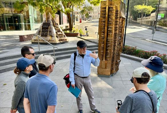 A group of people standing in a circle beside a large sculpture while listening to a tour guide during an experience with Urban Tours, Brisbane, Queensland © Urban Tours