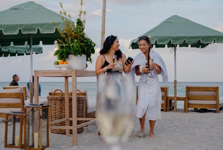 Two women walking under umbrellas at the beach at Pair'd, Margaret River, Western Australia © Tourism Western Australia
