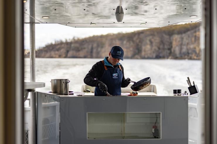 Man cooks seafood on the back of a boat on a tour with Tasmanian Wild Seafood Adventures, Hobart, Tasmania © Dearna Bond