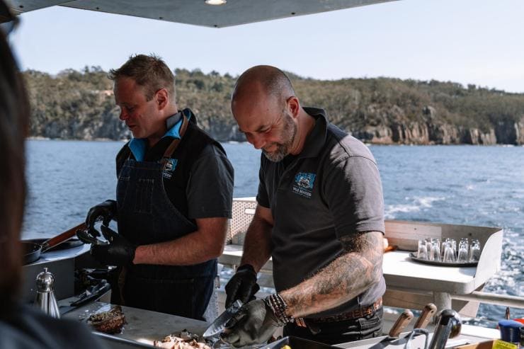 Two men cooking freshly caught lobster with Tasmanian Wild Seafood Adventures, Hobart, Tasmania © Tourism Australia