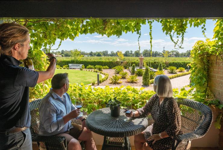 A couple looks out onto green gardens and vines at Elderton Wines, Barossa, South Australia © Tourism Australia