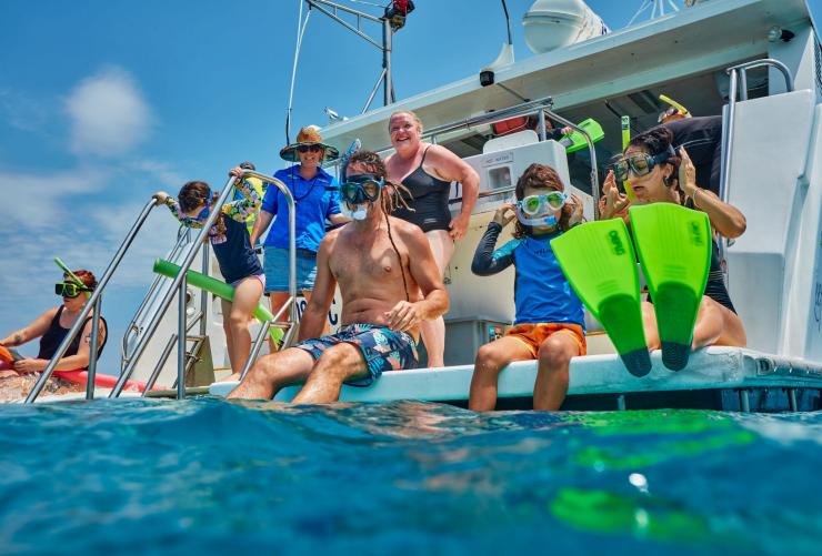 A family wearing snorkel gear prepares to jump into the water from the back of a boat with Mission Beach Dive, Great Barrier Reef, Queensland © Tourism Australia