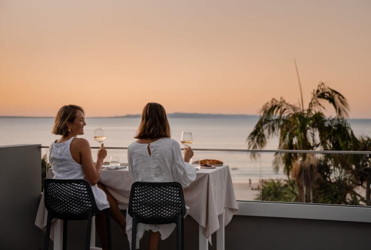 Two women drinking wine overlooking the ocean at Noosa Heads, Sunshine Coast, Queensland © Tourism Australia