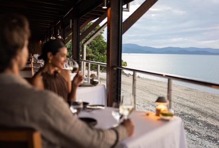 A couple dines at a restaurant overlooking the beach on Hamilton Island, Whitsundays, Queensland © Tourism Australia