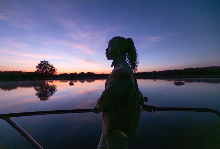 Woman looking out at the sunset from a Yellow Water Cruise, Kakadu National Park, Northern Territory © Tourism NT/Helen Orr