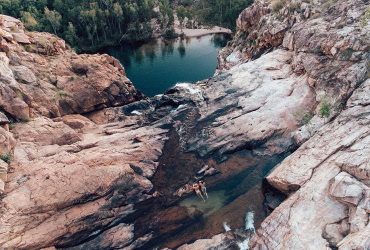 Two people lay in a calm pool on top of Gunlom Falls, Kakadu National Park, Northern Territory © Tourism Australia