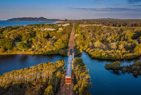 Ảnh chụp từ trên cao tàu Byron Solar di chuyển qua vùng cây bụi, Lạch Belongil, thị trấn Byron Bay, Tiểu bang New South Wales © Byron Solar Train