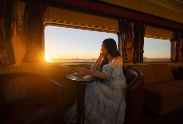 Một người phụ nữ đang thưởng thức đồ uống nóng trên Tàu The Ghan, Lãnh thổ phía Bắc © Tourism NT/Daniel Tran