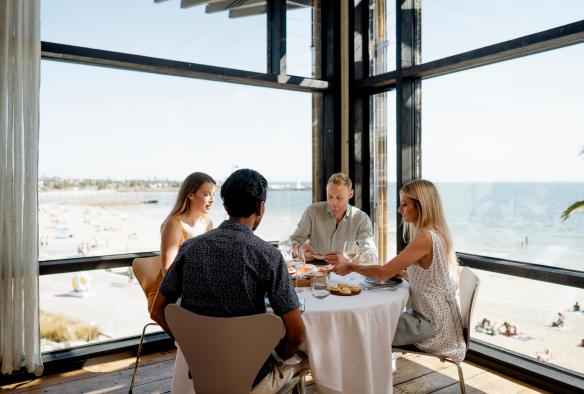 一群朋友坐在維多利亞州墨爾本（Melbourne）Stokehouse角落的餐桌前進餐©Stokehouse