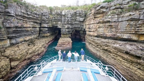 新南威爾士州傑維斯海灣Jervis Bay Wild觀光團的遊覽船在懸崖間駛過海口©澳洲旅遊局
