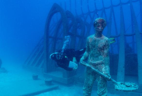 在昆士蘭州湯斯維爾的海底藝術博物館，水肺潛水員在一座水底展品旁游動©Gemma Molinaro Photography