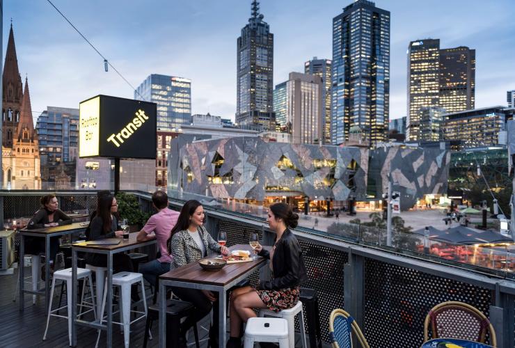 兩位女士在維多利亞州墨爾本Transit Rooftop Bar品嚐飲料和欣賞墨爾本的市區景觀©維多利亞旅遊局